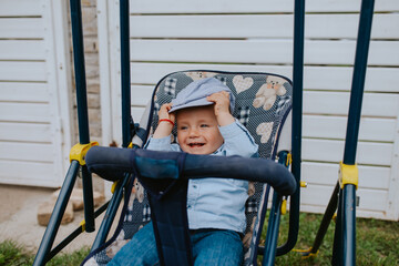 A beautiful child with a hat in a stroller in the yard