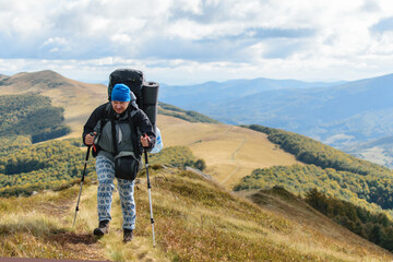 Fototapeta na wymiar A middle-aged man with a large backpack hiking in the mountains.