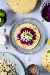 Fish tacos ready for serving top view with purple cabbage salsa, Mexican crema with lime and sour cream on flour tortilla and marinated sea bass fish in lime