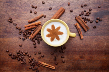 Top view of a cup of coffee with cream decorated. Food art creative concept image, drawing with cinnamon powder over wooden background.
