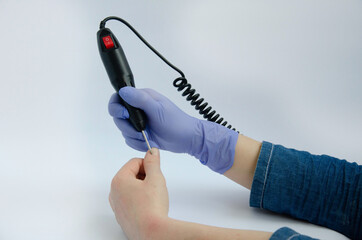 Nail engraver tool in hand preparing nail engraver on a white background
