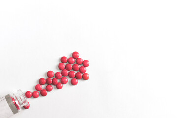 Red pills spilling out of bottle isolated on white background. Top view with copy space.