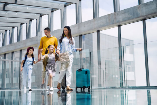 Family With Two Children Going On Holiday, Walking At The Airport With Luggage.