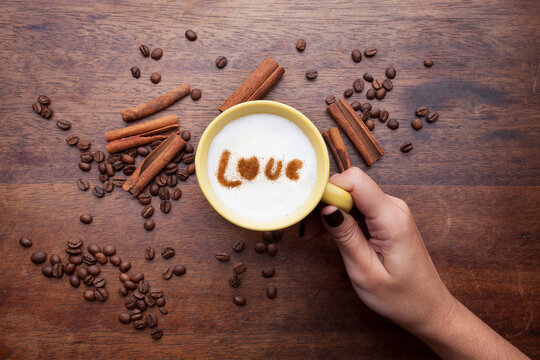 A retro cup with coffee cream. Food art creative concept image, cute drawing with cinnamon powder over milk cream on a wooden background.