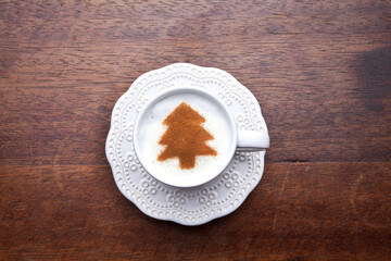 A retro cup with coffee cream. Food art creative concept image, cute drawing with cinnamon powder over milk cream on a wooden background.