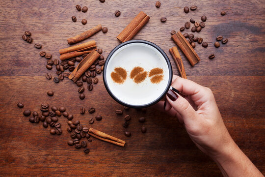 A retro cup with coffee cream. Food art creative concept image, cute drawing with cinnamon powder over milk cream on a wooden background.