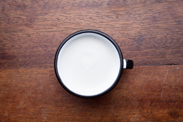 A retro cup with coffee cream. Food art creative concept image, cute drawing with cinnamon powder over milk cream on a wooden background.