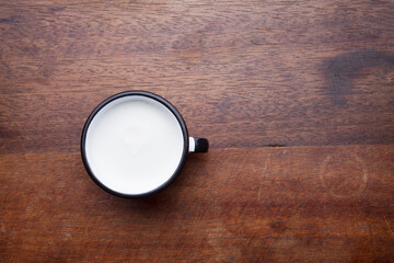 Fototapeta premium A retro cup with coffee cream. Food art creative concept image, cute drawing with cinnamon powder over milk cream on a wooden background.