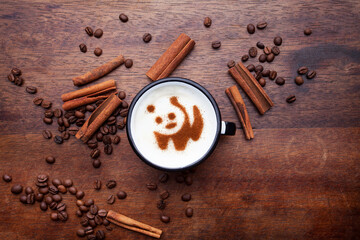 A retro cup with coffee cream. Food art creative concept image, cute drawing with cinnamon powder over milk cream on a wooden background.