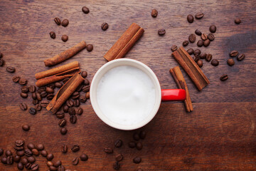 A retro cup with coffee cream. Food art creative concept image, cute drawing with cinnamon powder over milk cream on a wooden background.