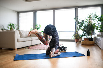 Young man doing workout exercise indoors at home, headstand.