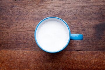 A rustic mug with coffee cream. Food art creative concept image, drawing with cinnamon powder over wooden background.