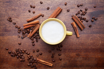 A rustic mug with coffee cream. Food art creative concept image, drawing with cinnamon powder over wooden background.