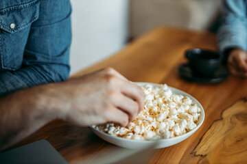 Man eating popcorn at home, close-up.