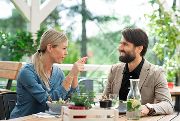 Happy couple sitting outdoors on terrace restaurant, talking.