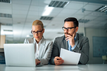 Portrait of a serious company management working with laptop.