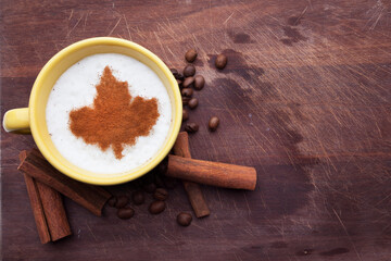 A rustic mug with coffee cream. Food art creative concept image, drawing with cinnamon powder over wooden background.