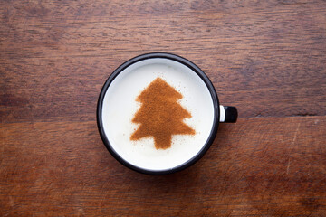 A rustic mug with coffee cream. Food art creative concept image, drawing with cinnamon powder over wooden background.