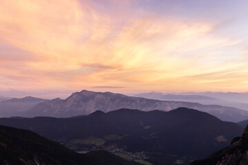 Naklejka na ściany i meble Mountain landscape at sunset in Julian Alps. Amazing view on colorful clouds and layered mountains silhouettes.