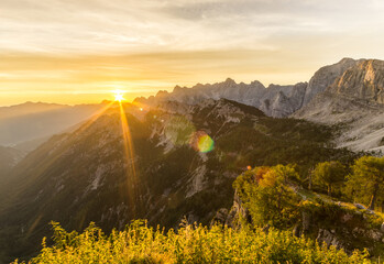 Amazing sunrise in the mountains. Backlight Sunlight with beautiful lens flares and sunbeams. Julian Alps, Triglav National Park, Slovenia, Mountain Slemenova, Sleme.