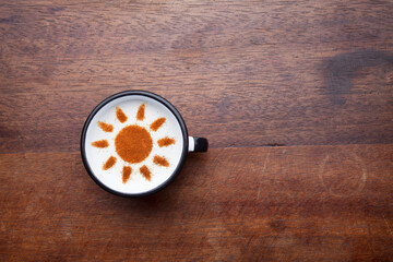 A rustic mug with coffee cream. Food art creative concept image, drawing with cinnamon powder over wooden background.