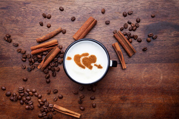 A rustic mug with coffee cream. Food art creative concept image, drawing with cinnamon powder over wooden background.