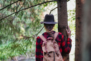 Rear view of young woman on a walk outdoors in forest in summer nature.