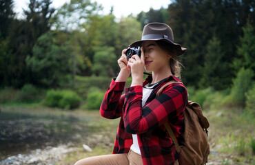 Young woman with a dog on a walk outdoors in summer nature, taking photographs.