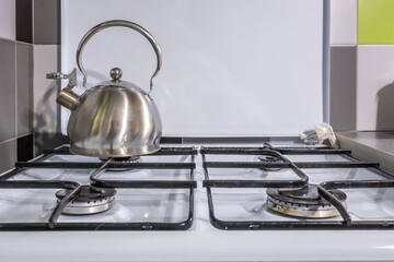 gas stove cooker on four burners with teapot in the kitchent