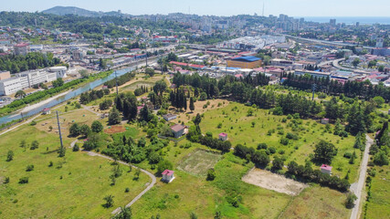 Fototapeta na wymiar Beautiful aerial panoramic view of multi-storey buildings against the background of mountains. Residential development near water intake structures in the riverbed. Sochi, Russia.