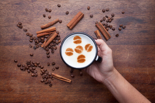A rustic mug with coffee cream. Food art creative concept image, drawing with cinnamon powder over wooden background.
