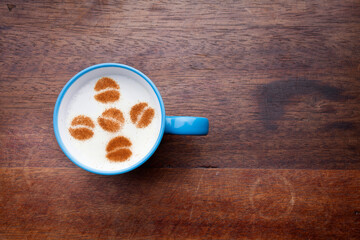 A rustic mug with coffee cream. Food art creative concept image, drawing with cinnamon powder over wooden background.

