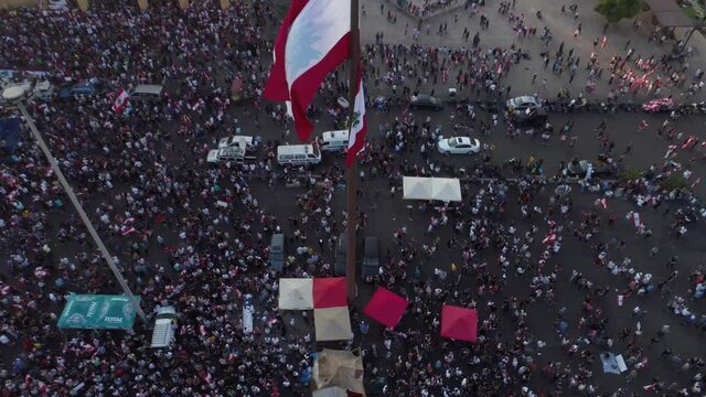 Beirut, Lebanon 2019 : sunset drone shot starting from Lebanese flag to reveal martyrs square with hundreds of people revolting against government failure and corruption during the Lebanese revolution
