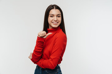 Photo of cheerful young woman smiling and pointing finger aside