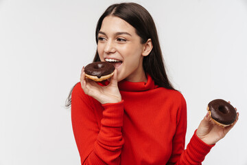Photo of cheerful brunette woman smiling and eating chocolate donuts