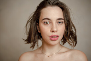 Fototapeta premium A young beautiful girl with a natural appearance. A beauty portrait. Girl looks into the camera with tousled hair