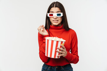 Photo of brunette woman wearing 3D glasses holding popcorn bucket