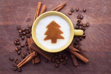 A rustic mug with coffee cream. Food art creative concept image, drawing with cinnamon powder over wooden background.
