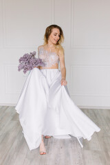 Fototapeta premium Beautiful girl woman bride in a delightful wedding dress with a bouquet of flowers dancing in front of a mirror portrait of a blonde with blue eyes holding