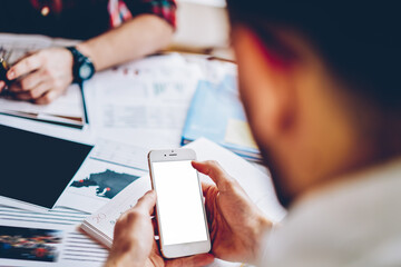 Selective focus on modern smartphone device with blank screen for your advertising content in male hands.Cropped view of young man installing app on cellular with mock up area using 4G internet