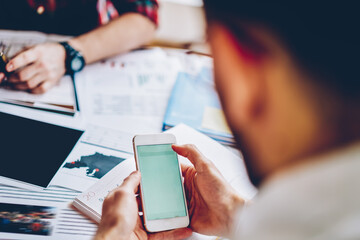 Cropped view of young man holding modern smartphone in hands to download files from websites via 4G internet.Selective focus on digital cellular with mobile calendar which using hipster blogger