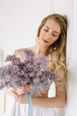 Beautiful girl woman bride in a delightful wedding dress with a bouquet of flowers dancing in front of a mirror portrait of a blonde with blue eyes