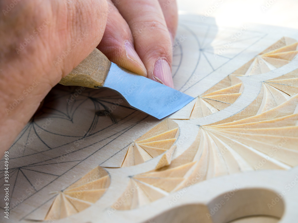 Wall mural Woodcarver knife creates a geometric pattern on a wooden board.