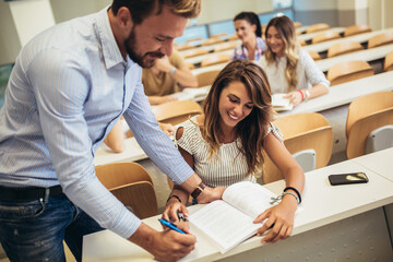  Group of smiling students and teacher with notebook in classroom