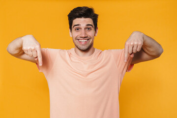 Photo of joyful handsome man smiling and pointing finger downward