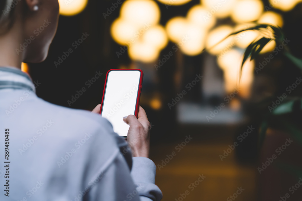 Aufkleber back view from shoulder of female person holding mobile phone with blank mock up screen while standi