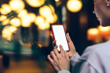 Back close up view of female person holding cellphone with big blank screen and reading...
