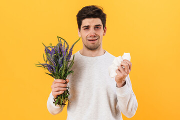 Photo of handsome unhappy man with allergy posing with flowers