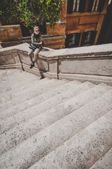 Young attractive blond woman tourist sitting alone on the stairs in Spanish steps in Rome, Italy