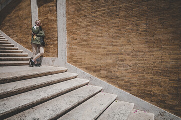 Young attractive blond woman tourist staying on the stairs in Spanish steps in Rome, Italy
